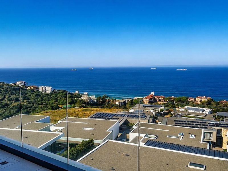 Elevated balcony view overlooking the coastline, featuring a modern frameless glass balustrade and tiled flooring.