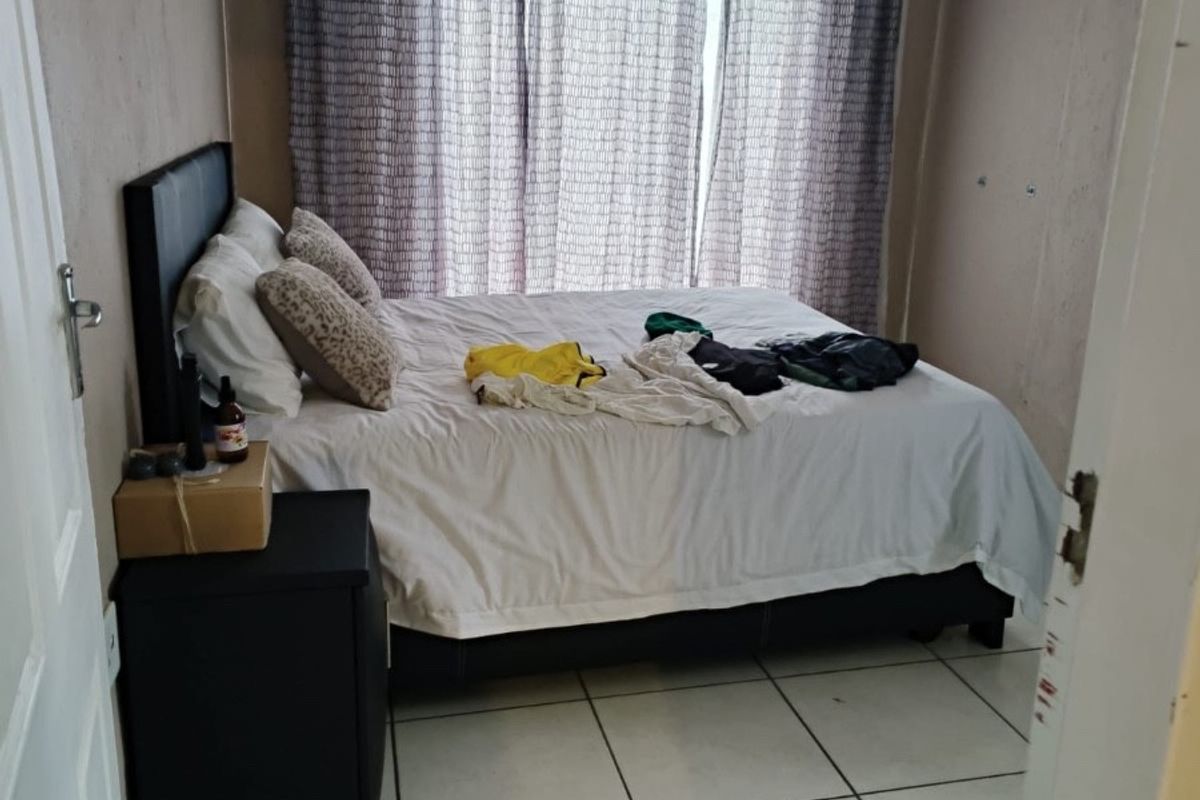 A functional bedroom featuring tiled flooring and large windows with curtain rails, offering a neutral base for potential interior updates.