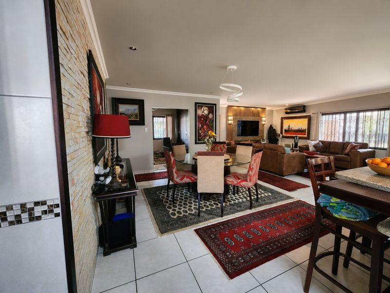 Spacious open-plan living and dining area featuring a stone-clad feature wall, tiled flooring, and a modern built-in media unit.