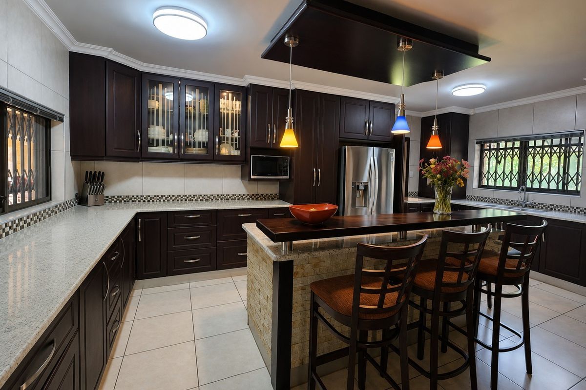 A well-appointed kitchen featuring dark wood cabinetry, granite countertops, a central island with breakfast bar seating, and modern stainless steel appliances.