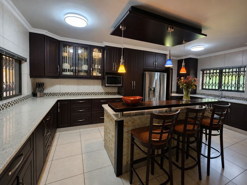 A well-appointed kitchen featuring dark wood cabinetry, granite countertops, a central island with breakfast bar seating, and modern stainless steel appliances.