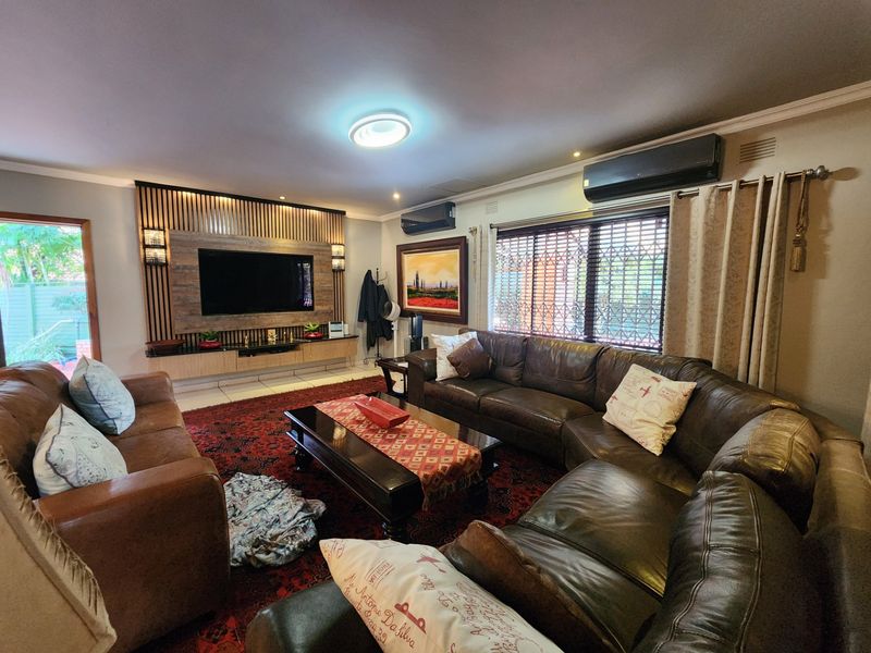 Spacious living room featuring a custom slatted timber media wall, built-in cabinetry, and wall-mounted air conditioning units.