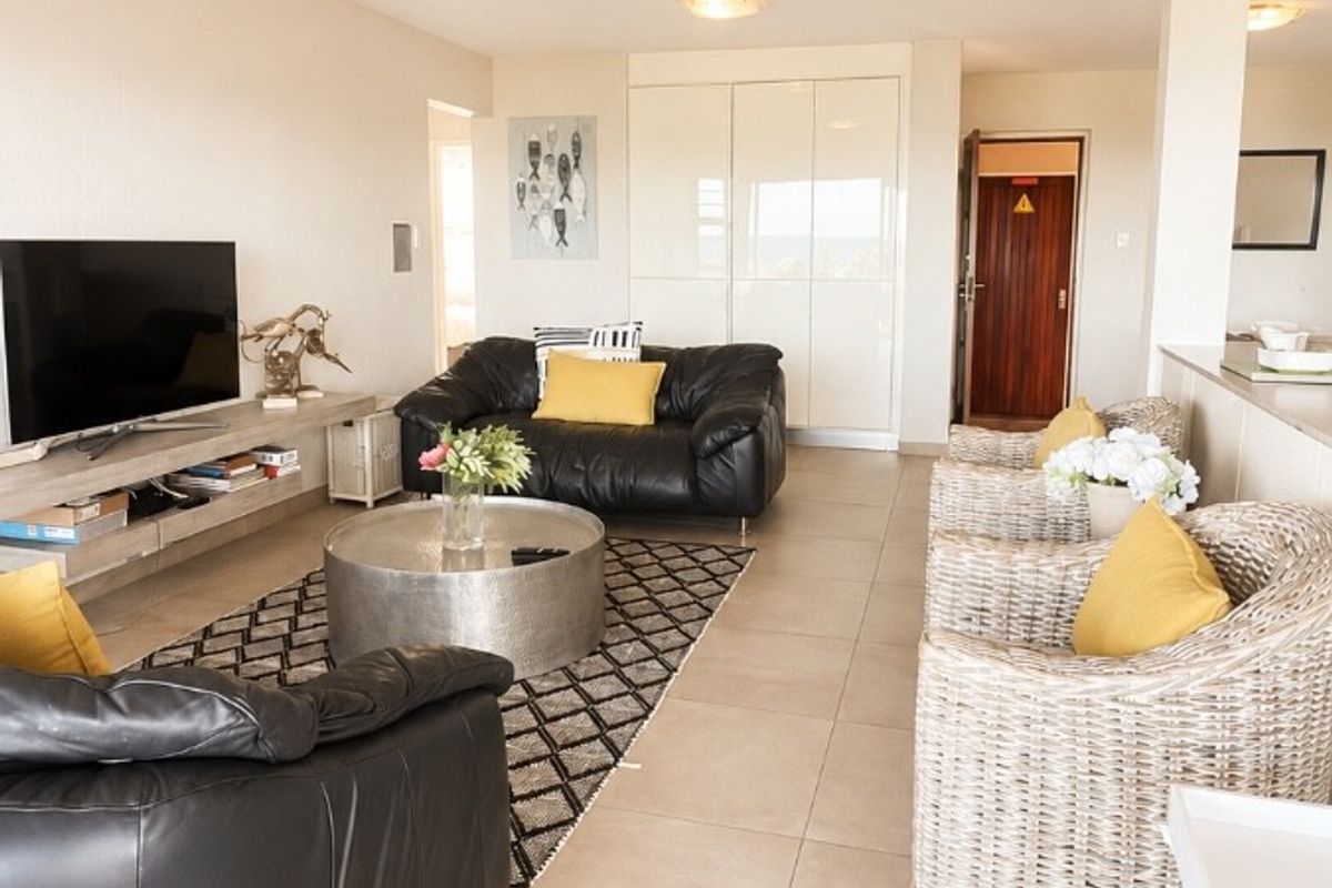 Spacious open-plan living area featuring neutral tiled flooring, built-in storage cupboards, and bright, functional lighting throughout the space.