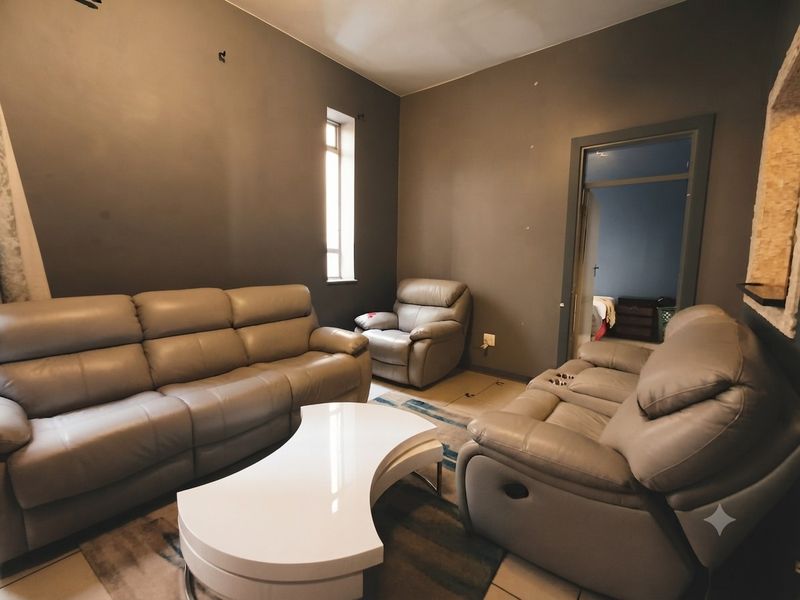 A living room featuring tiled flooring and dark painted walls, providing a functional space with access to an adjacent room.