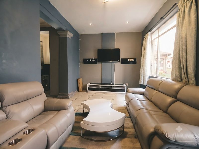 A comfortable living room featuring tiled flooring, recessed lighting, and a large window allowing for natural light.