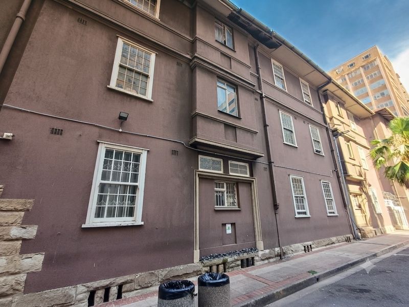 Exterior view of a multi-story apartment building facade featuring traditional sash windows and a stone foundation base.