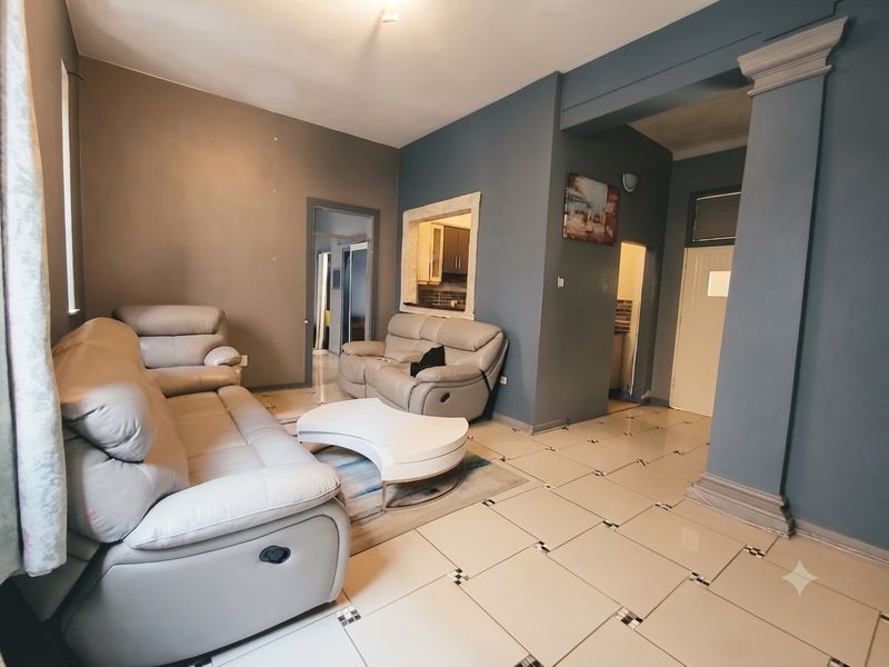 Spacious living area featuring tiled flooring, a decorative column, and a convenient pass-through window connecting to the kitchen area.