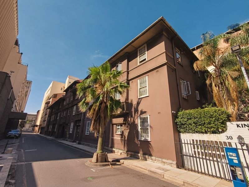 Street-level view of the apartment building facade featuring traditional sash windows and a secure gated entrance.