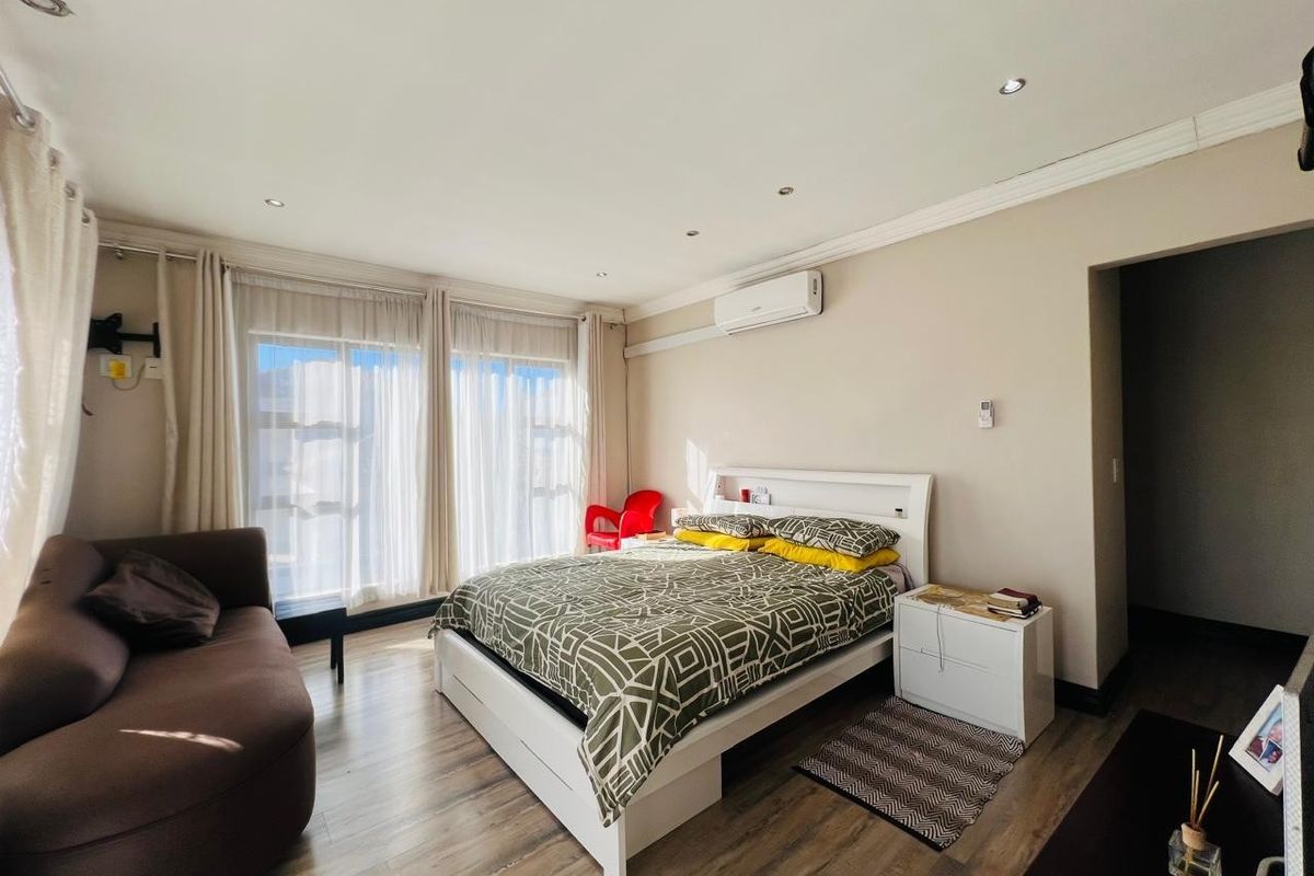 Spacious bedroom featuring laminate flooring, recessed downlighting, and a wall-mounted split-system air conditioner.
