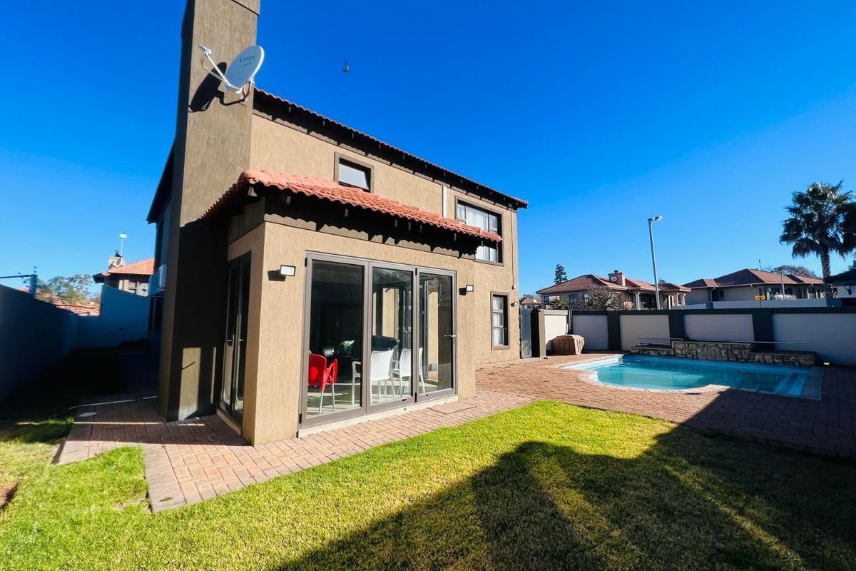 Rear view of the house featuring a paved patio area, a private swimming pool, and a well-maintained garden space.