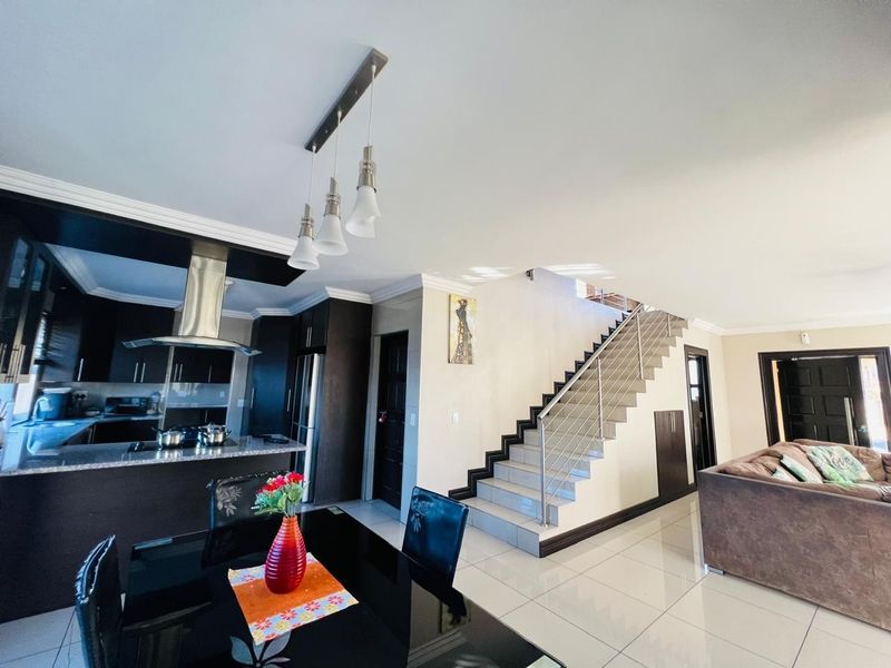 Spacious open-plan living area featuring a modern kitchen with granite countertops, sleek cabinetry, and a staircase with a stainless steel balustrade.