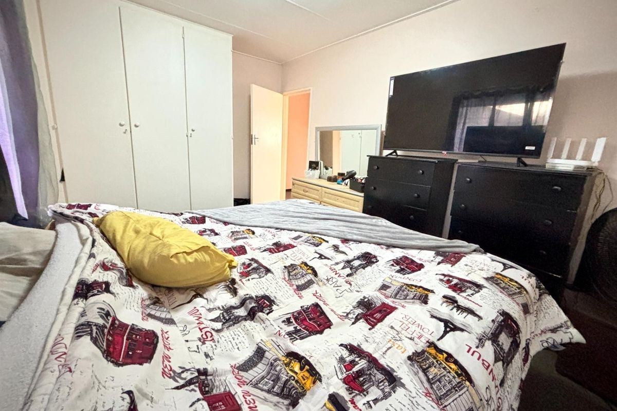 A functional bedroom featuring a built-in wardrobe and neutral wall finishes, providing a comfortable space for rest.