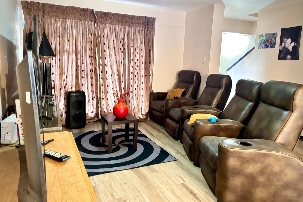 A living room area featuring light-toned laminate flooring and floor-to-ceiling curtains, providing a functional space for relaxation.