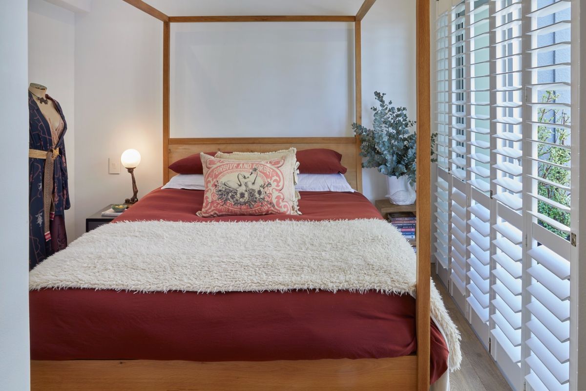 A well-lit bedroom featuring timber flooring and white plantation shutters, creating a bright and comfortable living space.