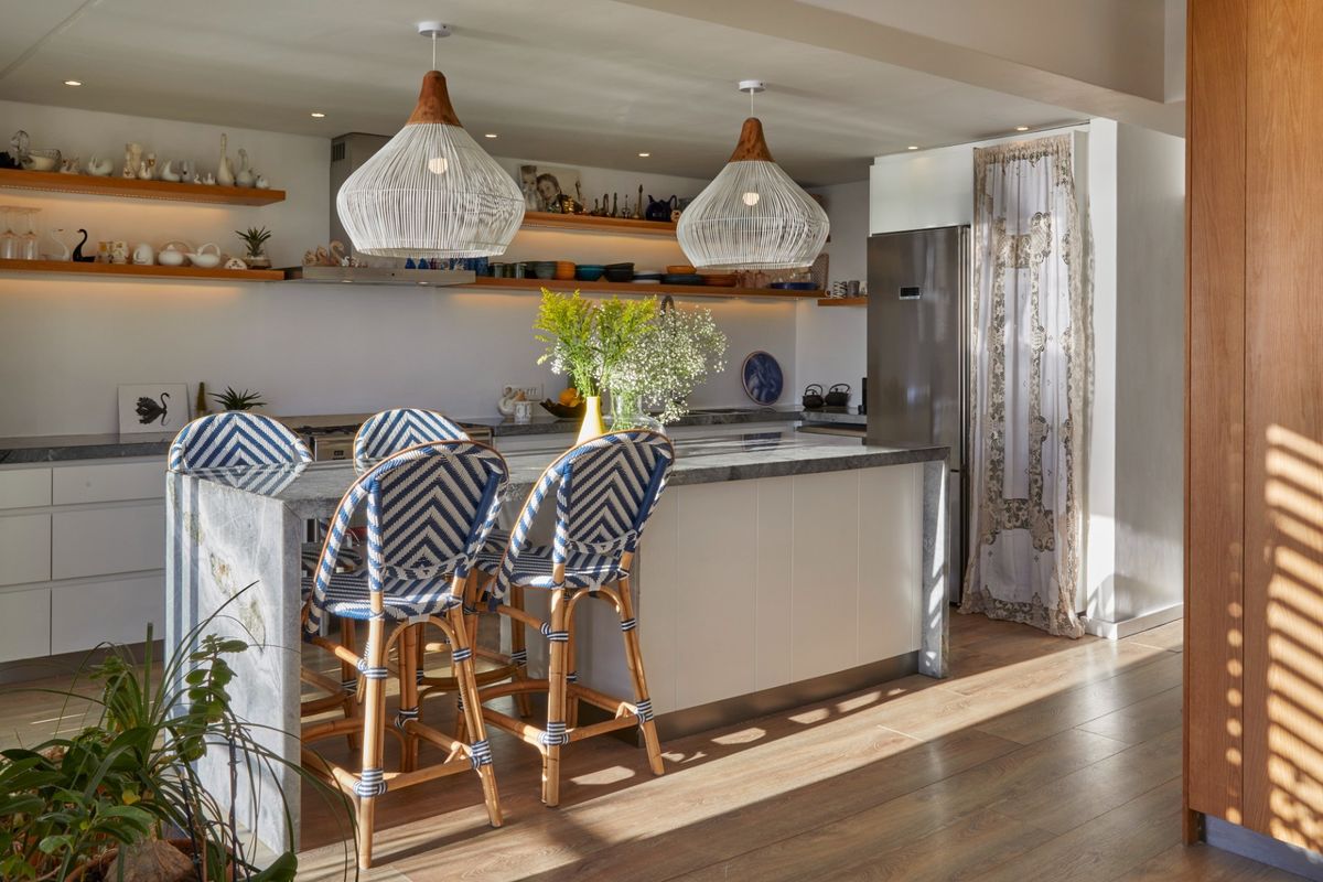 Modern kitchen featuring a stone-topped island, floating timber shelving, and integrated cabinetry, creating a bright and functional culinary space.