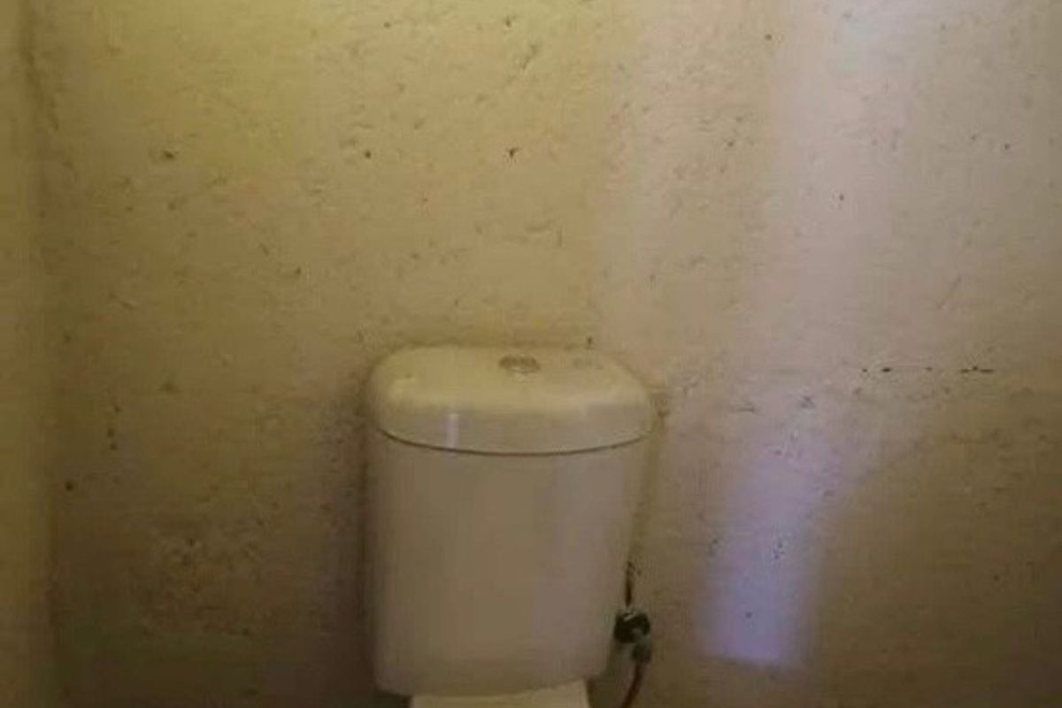 A small, basic bathroom featuring a standard toilet and plain wall finishes, currently in need of cosmetic updates and maintenance.