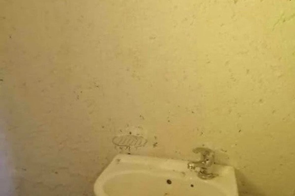 A basic bathroom area featuring a wall-mounted basin, showing significant signs of wear and requiring maintenance or renovation.