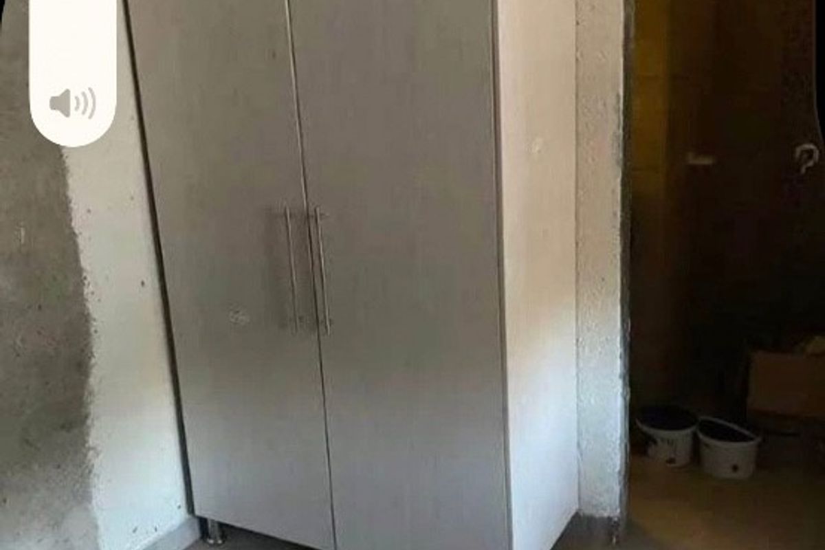 A bedroom space featuring a built-in wardrobe, tiled flooring, and unfinished wall surfaces requiring completion.