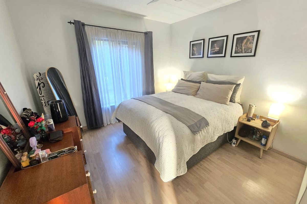 A well-lit bedroom featuring light-toned laminate flooring and a ceiling fan, offering a comfortable and functional living space.