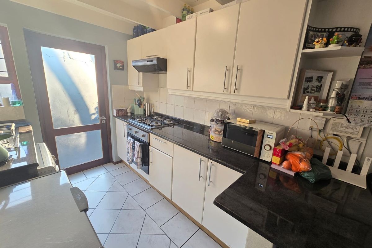 Functional kitchen featuring granite countertops, built-in cabinetry, gas hob, and direct access to an exterior door.