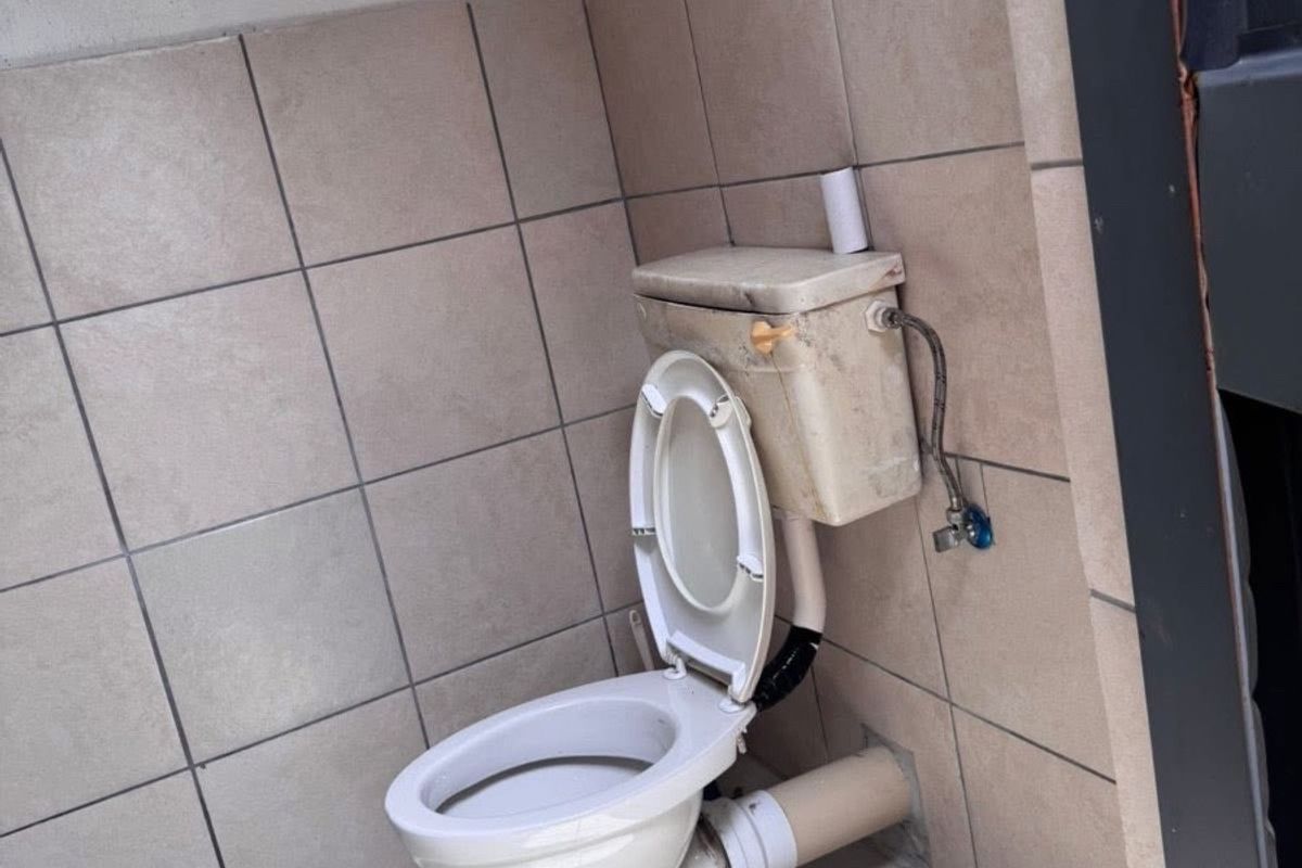 A small bathroom featuring tiled walls and flooring with a standard toilet fixture requiring maintenance and cosmetic updates.