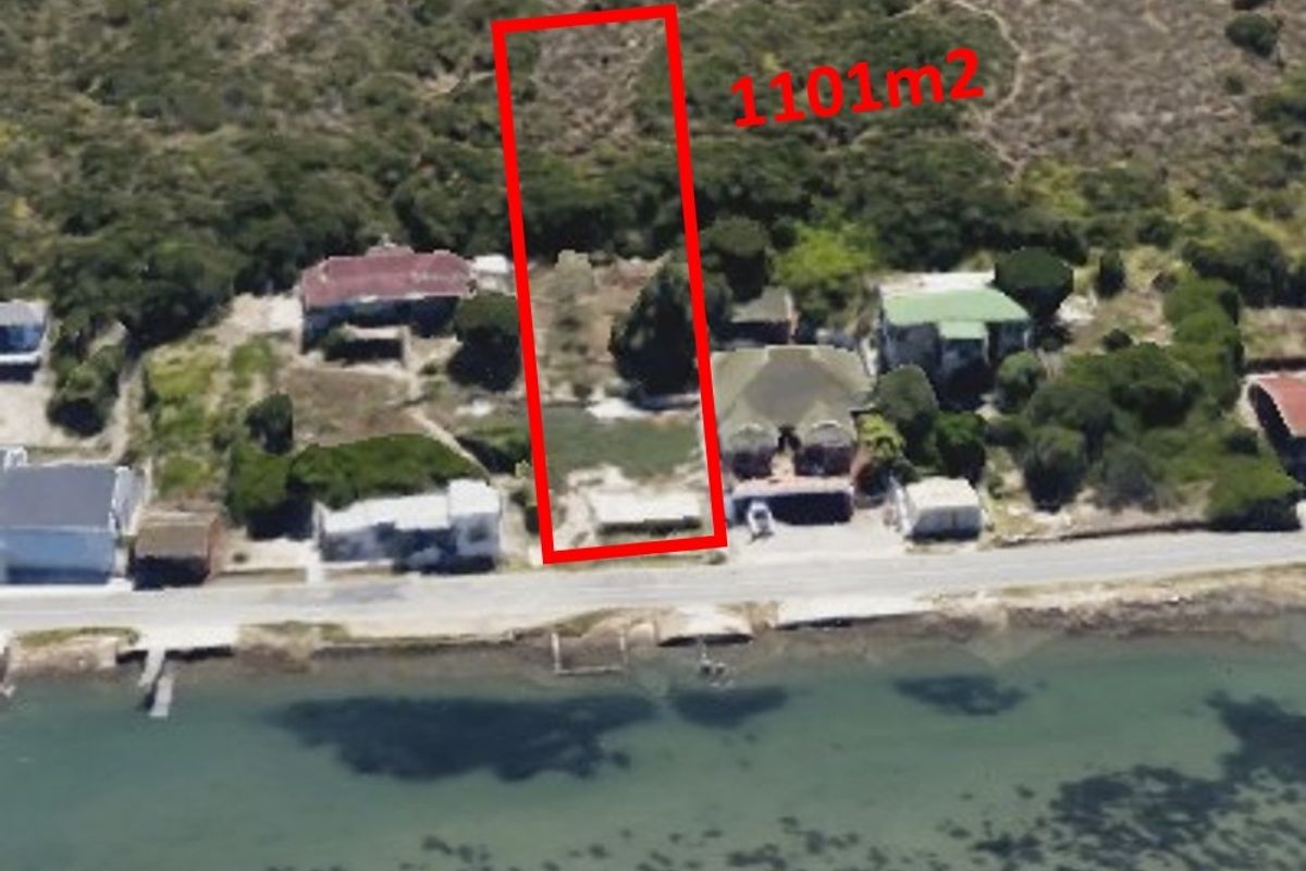 Aerial view of a 1101m2 vacant residential plot situated along the coastline, offering potential for development.