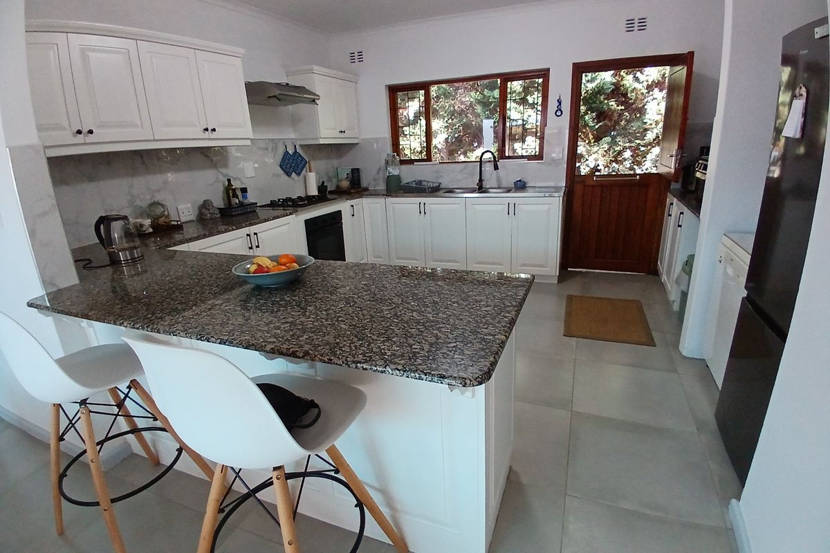 A well-maintained kitchen featuring white cabinetry, granite countertops, a gas hob, and a stable door leading to the exterior.