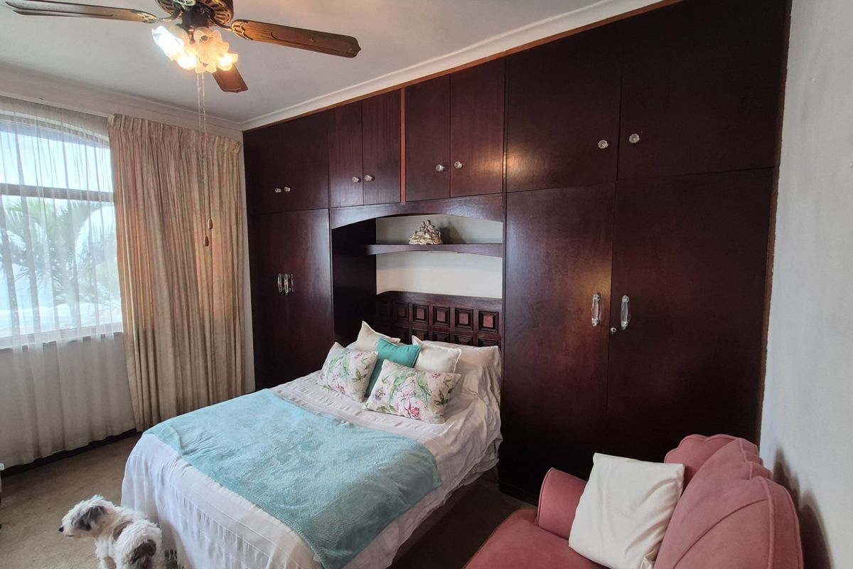 A bedroom featuring extensive dark wood built-in cabinetry and a ceiling fan, offering ample storage space.