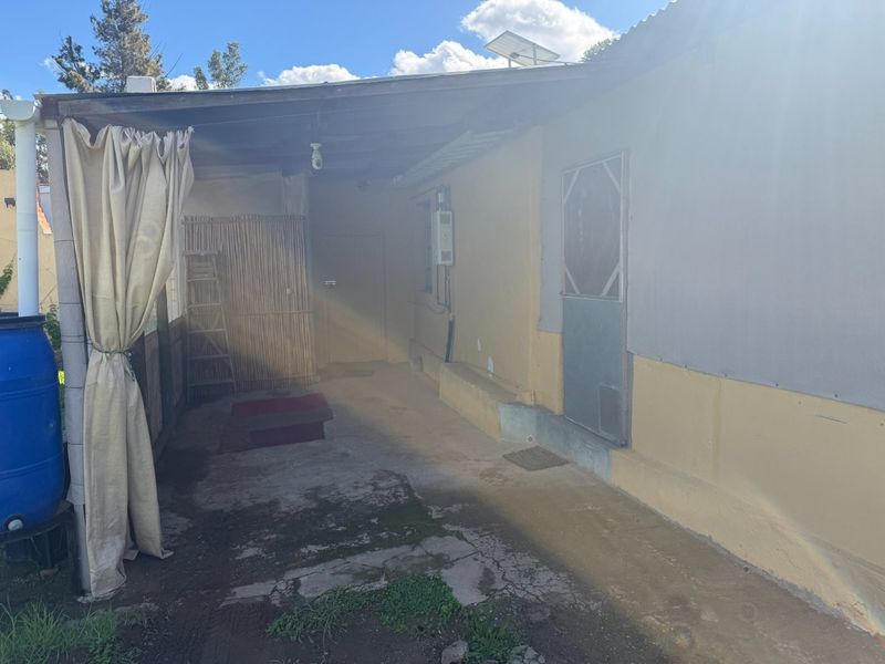 A covered outdoor patio area featuring concrete flooring and direct access to the home, requiring maintenance and cosmetic updates.
