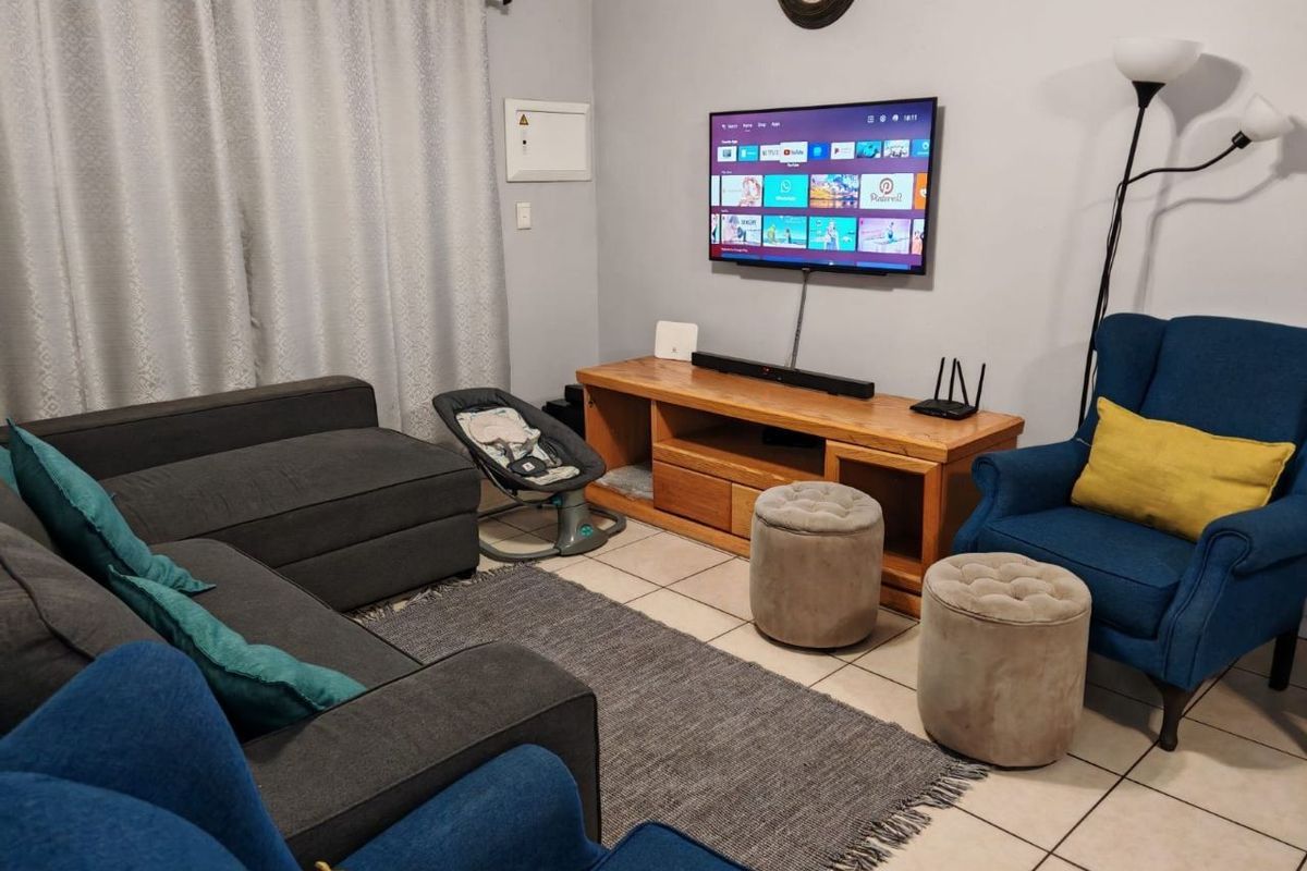 A comfortable living room featuring tiled flooring and a wall-mounted television setup, providing a functional space for relaxation.
