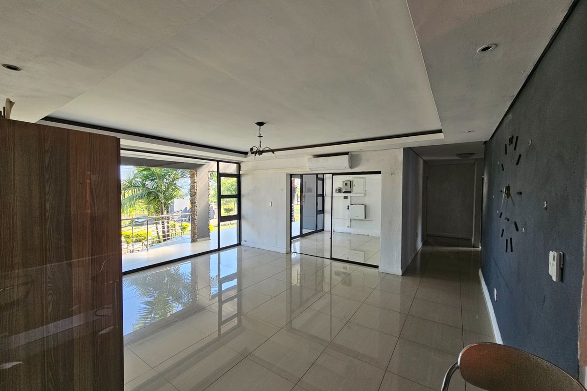 Spacious, light-filled living area featuring large format floor tiles, a split-system air conditioner, and seamless access to an outdoor patio through sliding glass doors.