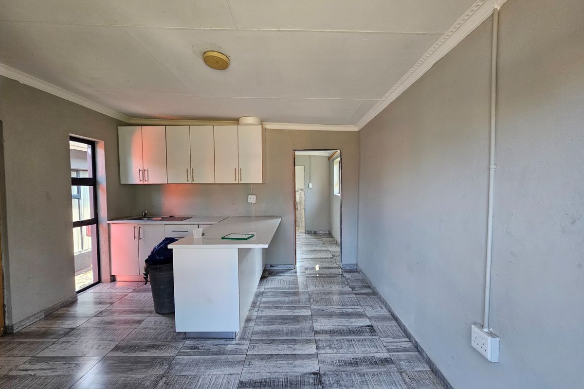 A functional kitchen area featuring built-in cabinetry, a sink, and tiled flooring, offering a clean, blank canvas for potential updates or modern styling.
