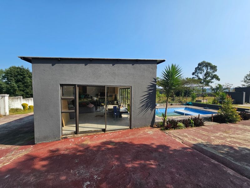 Rear view of the property featuring a swimming pool, sliding glass doors, and a paved patio area.