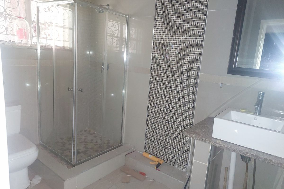 A bathroom featuring a glass shower enclosure, mosaic tile accent wall, and a modern vessel sink on a stone vanity countertop.
