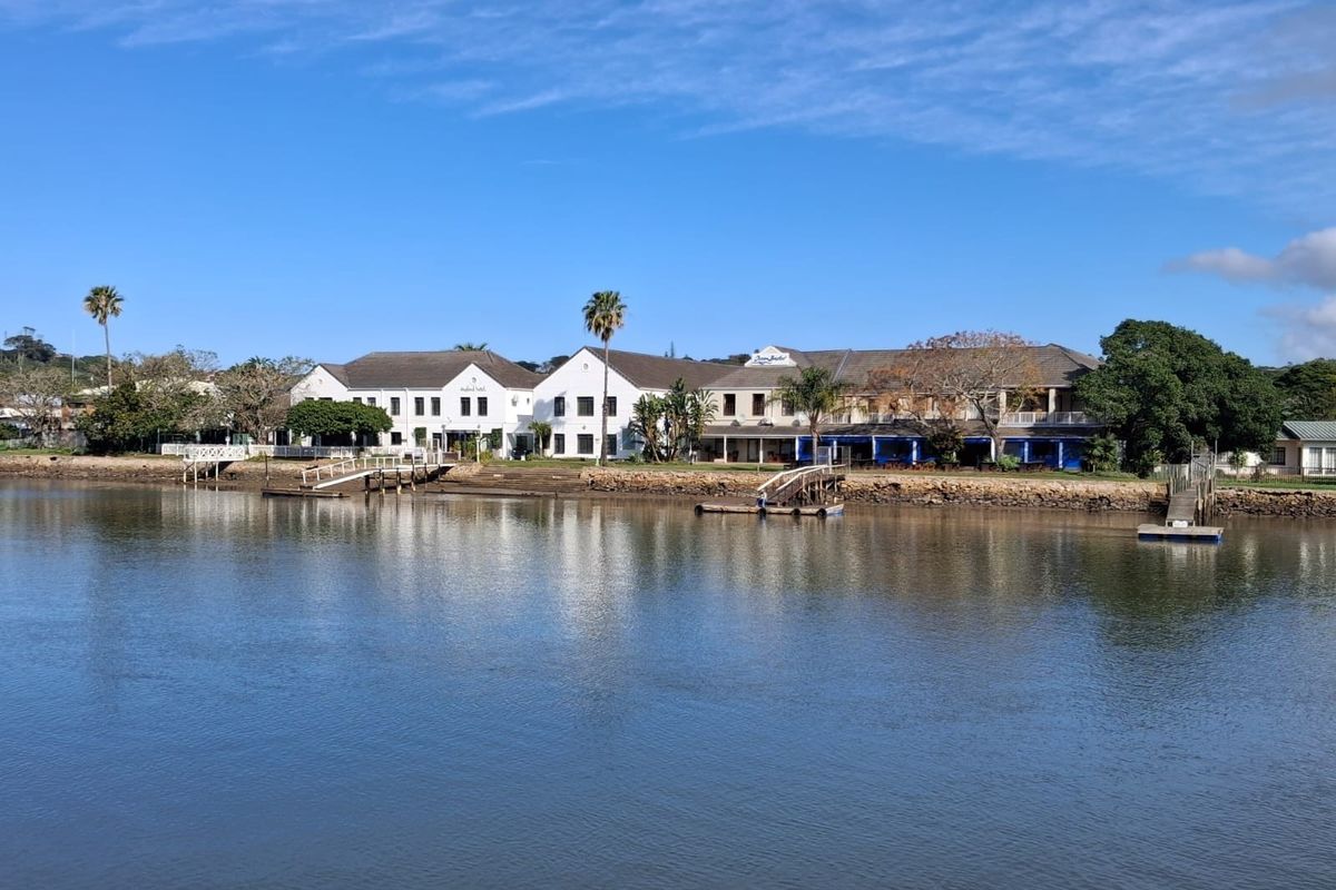 A scenic view of a commercial property complex situated along a riverbank, featuring private jetties and well-maintained landscaped grounds.