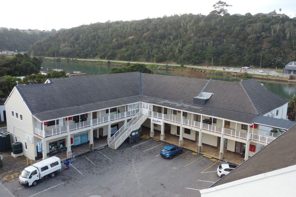 Aerial view of a commercial property featuring a multi-level building with balconies, an external staircase, and a paved parking area.