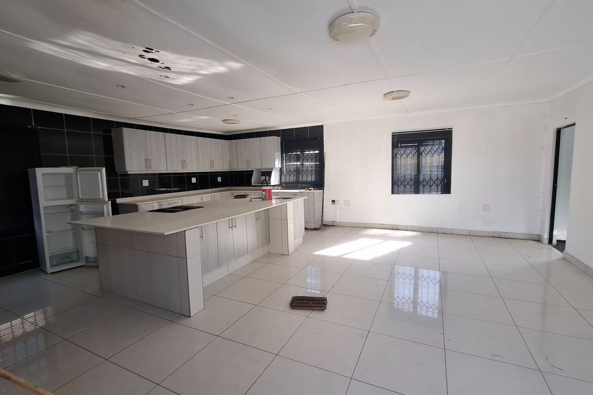Spacious open-plan kitchen and living area featuring tiled floors, built-in cabinetry, and a central island, offering a blank canvas for modern interior design.