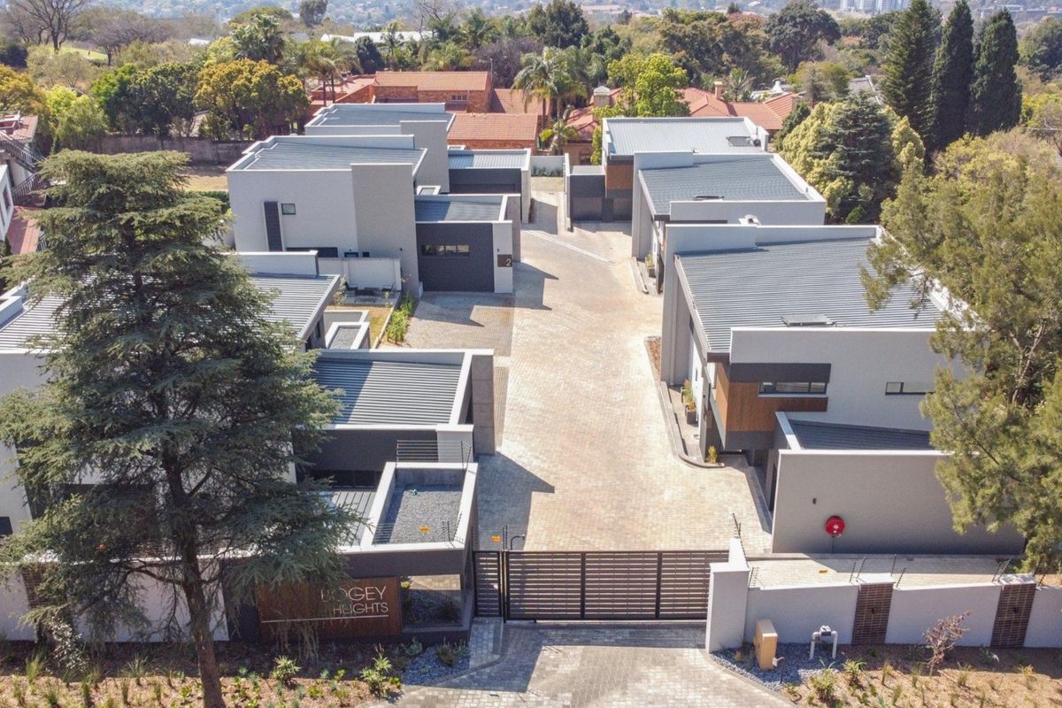 Aerial view of a modern residential complex featuring paved driveways, secure gated access, and contemporary flat-roofed architectural units.