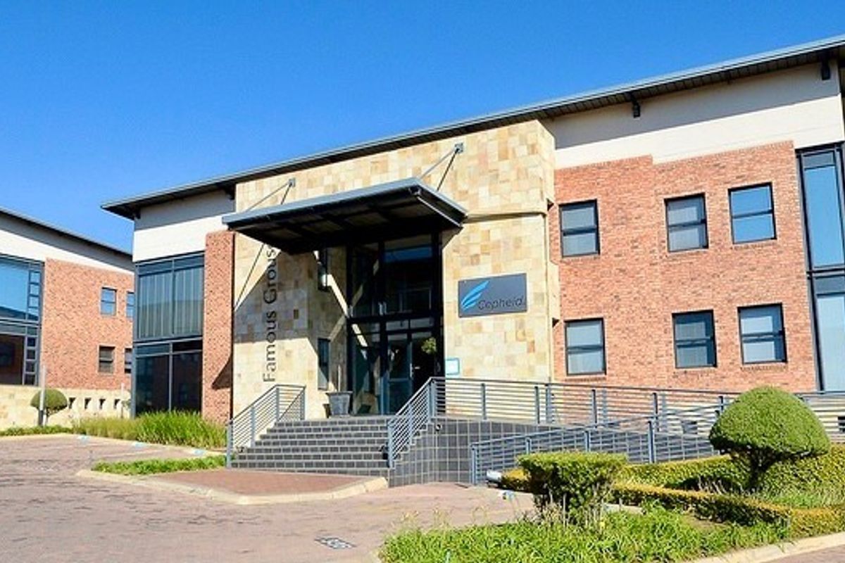 A professional commercial office building featuring a brick and stone facade, paved driveway, and landscaped grounds with accessible ramp and stair entry.