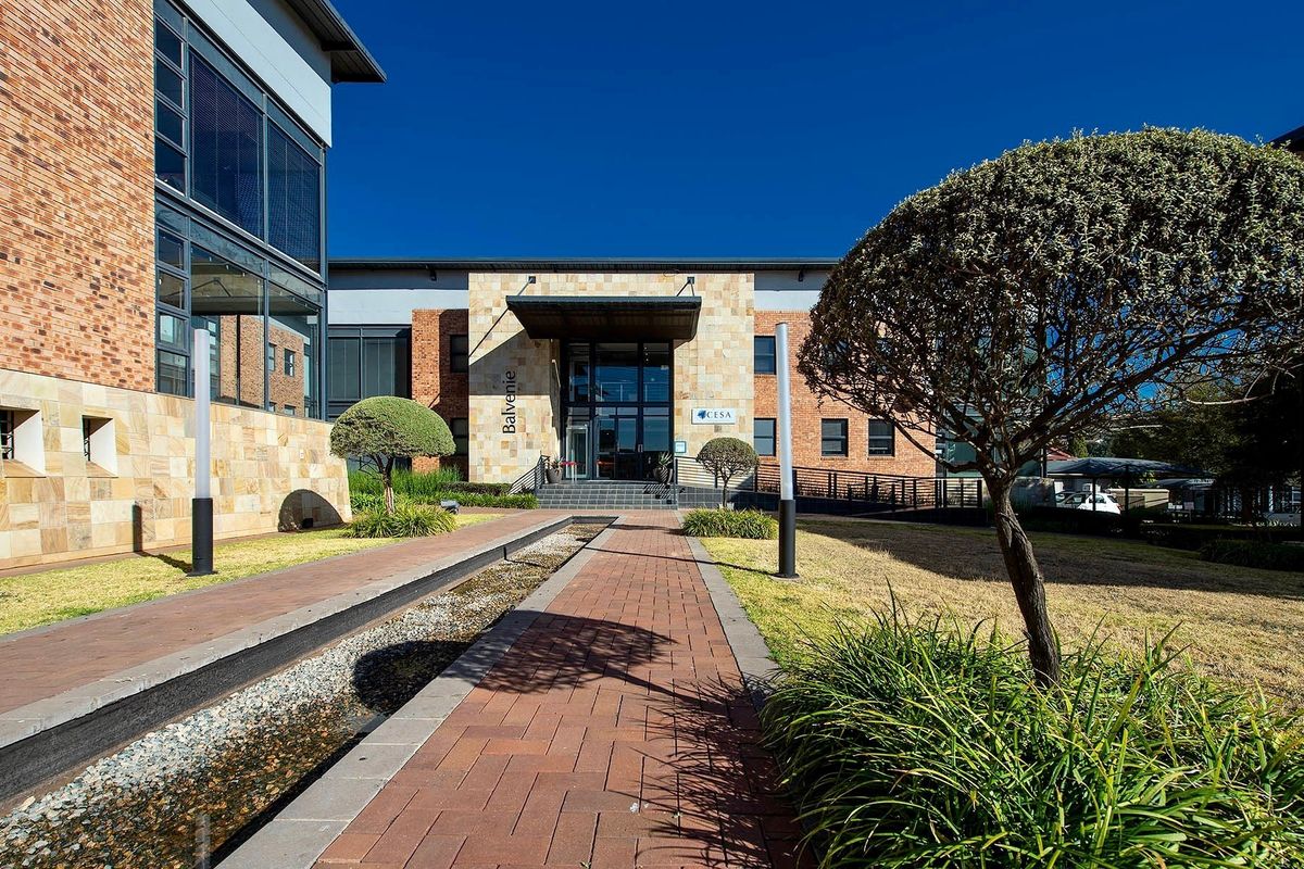 A professional exterior view of the Balvenie commercial building, featuring a paved walkway, landscaped garden, and modern brick and stone facade.