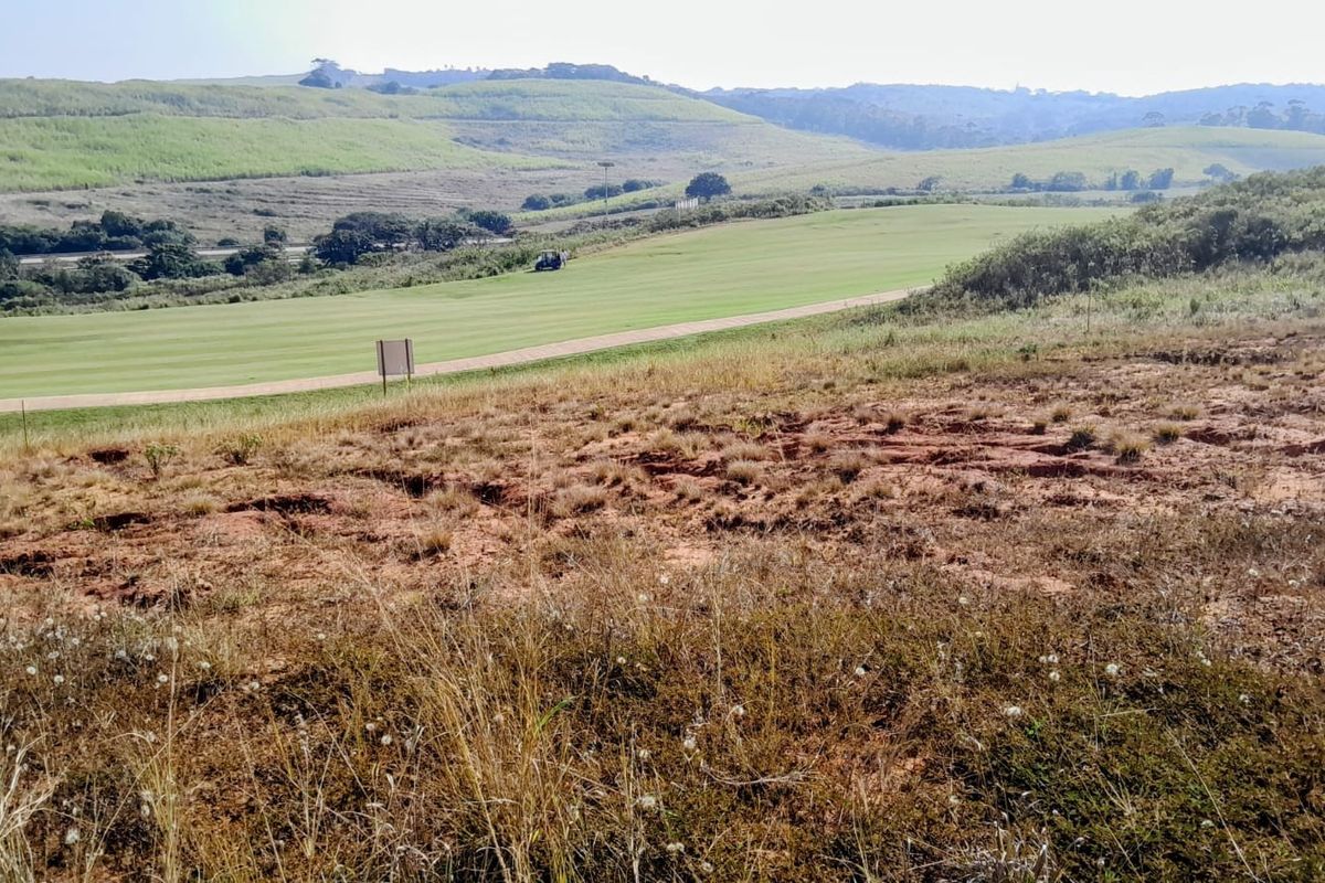 A scenic view overlooking a vacant residential plot with rolling green hills and landscape in the background.