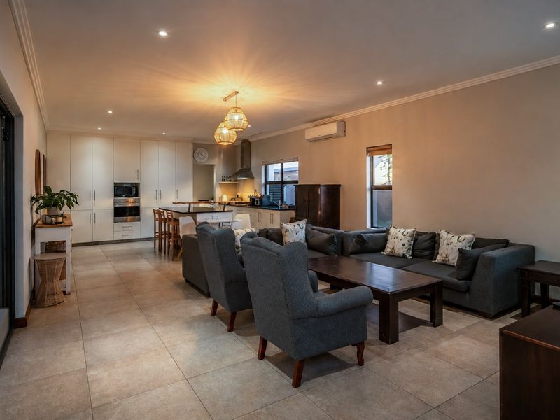 Spacious open-plan living and kitchen area featuring modern cabinetry, integrated appliances, tiled flooring, and seamless access to the outdoor patio through sliding glass doors.