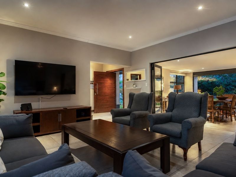 Spacious living room featuring tiled flooring, recessed downlighting, and large bi-fold doors providing seamless access to the outdoor patio area.