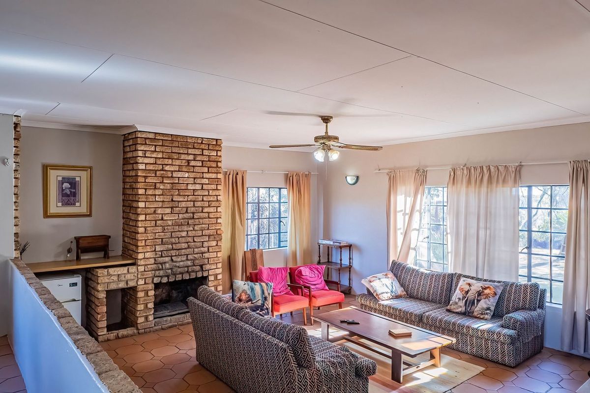 Spacious living room featuring a prominent brick fireplace, tiled flooring, and a ceiling fan, offering a comfortable and traditional farm-style atmosphere.