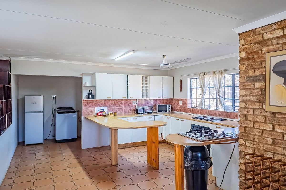 Spacious kitchen featuring built-in cabinetry, a gas hob, tiled backsplash, and an exposed brick feature wall, offering a functional layout with ample counter space.