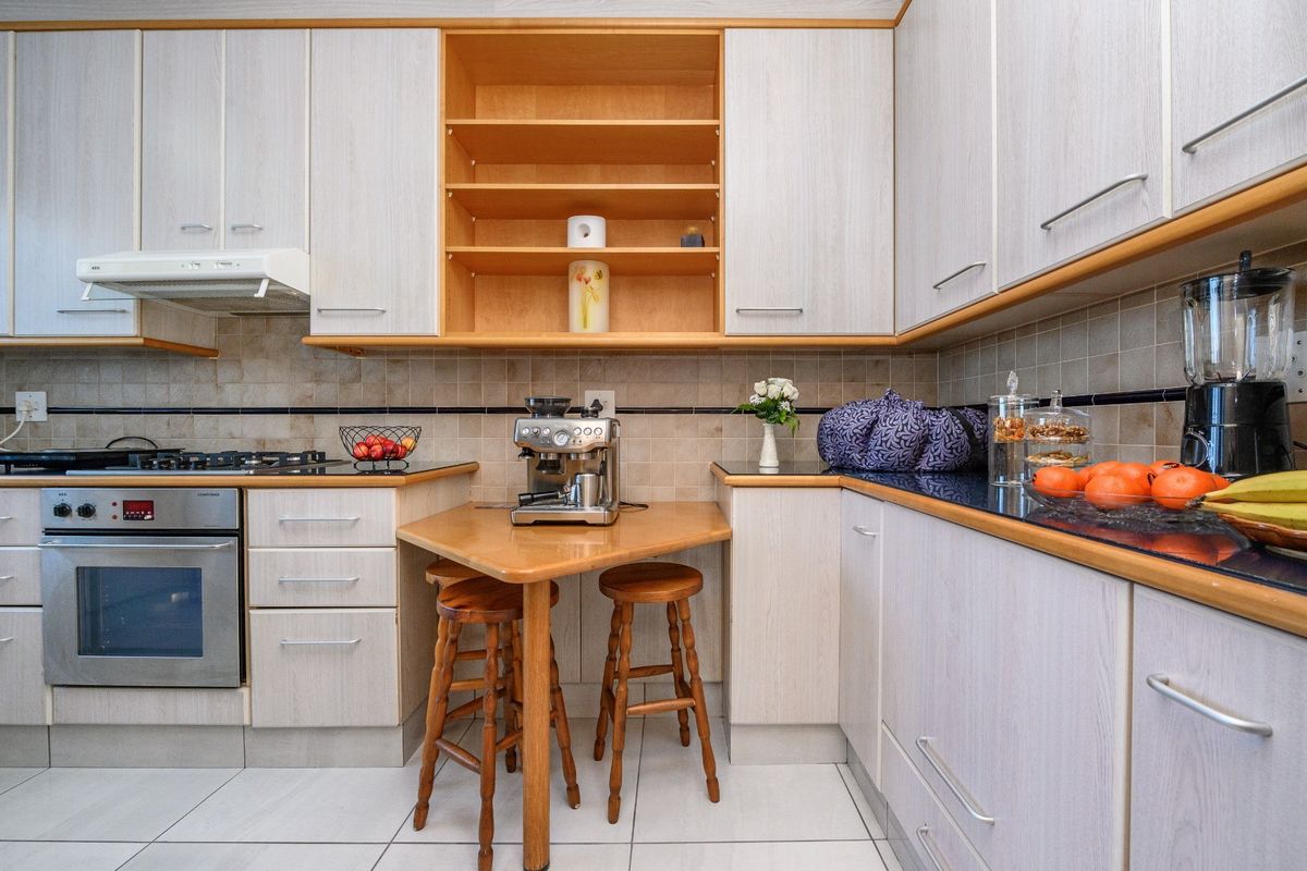 A functional kitchen featuring light wood-grain cabinetry, granite countertops, a gas hob, and an integrated oven with a tiled backsplash.