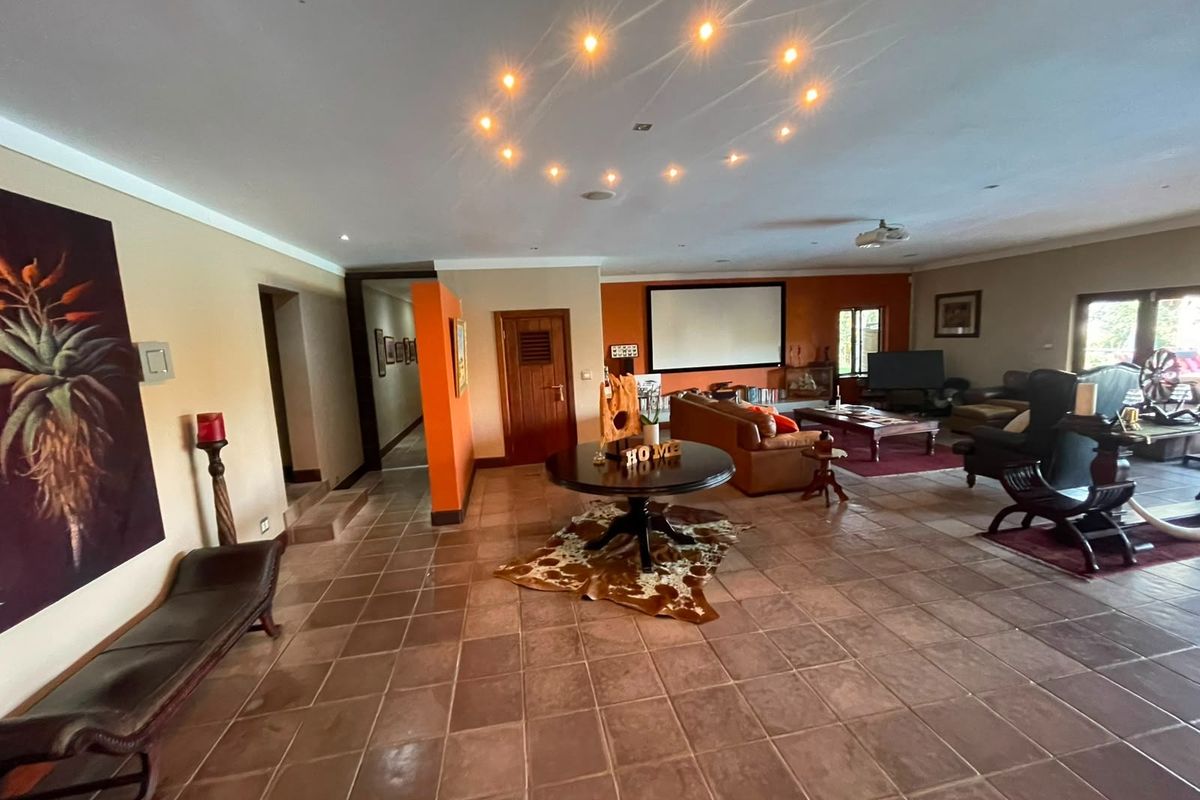 Spacious living area featuring tiled flooring, recessed lighting, and a built-in projector screen, offering a versatile space for entertainment and relaxation.