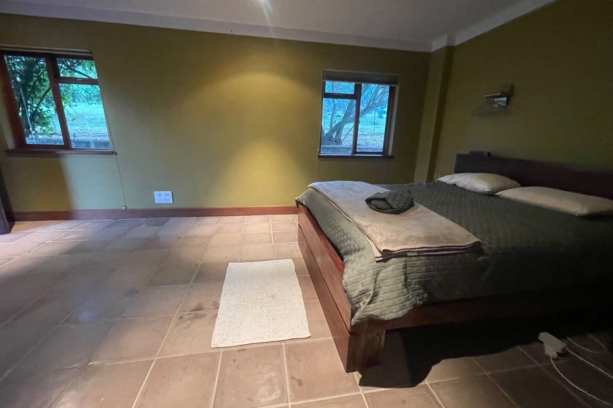 A spacious bedroom featuring tiled flooring, cove cornicing, and dual windows, offering a neutral canvas for potential interior updates.