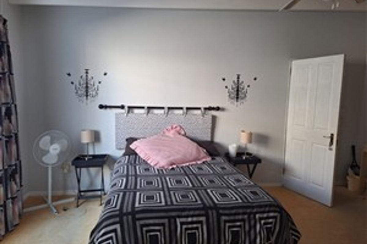 A standard bedroom featuring a ceiling fan and a classic panel door, providing a functional and comfortable living space.