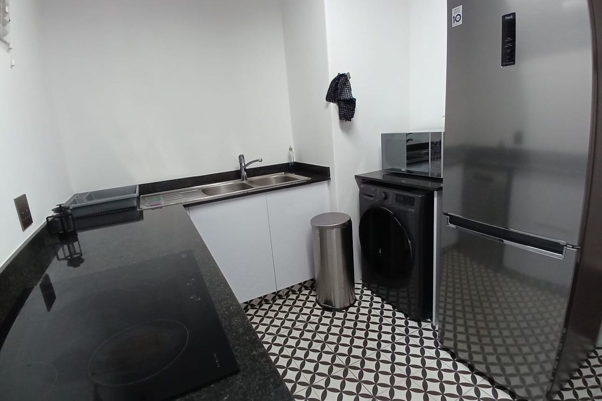 A modern kitchen featuring granite countertops, a built-in electric hob, stainless steel sink, and stylish patterned floor tiles.